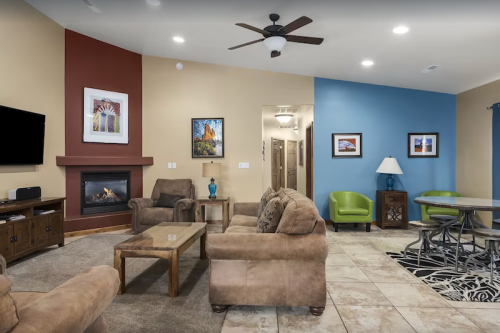 Cozy living room with a fireplace, comfortable seating, and colorful walls, featuring artwork and a dining area.