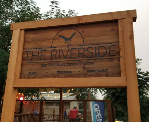 Wooden sign for "The Riverside," established 2016, with the slogan "Eat, Drink, Repeat."