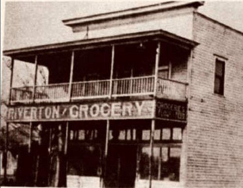 Historic Riverton Grocery storefront with a balcony, featuring large signage and a classic wooden structure.