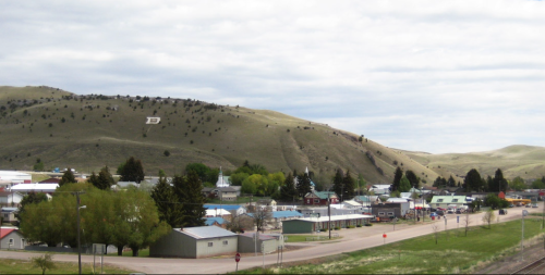 A small town nestled in a valley, with hills in the background and a large letter "D" on the hillside.