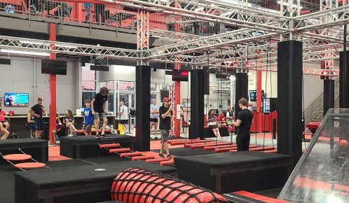 A vibrant indoor obstacle course with participants navigating various challenges in a red and black setting.