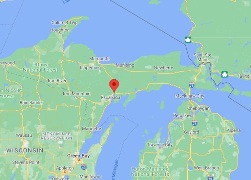 Map showing Escanaba, Michigan, marked with a red pin, surrounded by nearby towns and waterways.