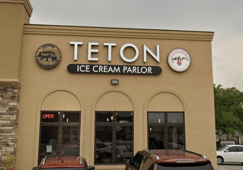 Exterior of Teton Ice Cream Parlor, featuring a sign with the name and logo, and an "Open" sign in the window.
