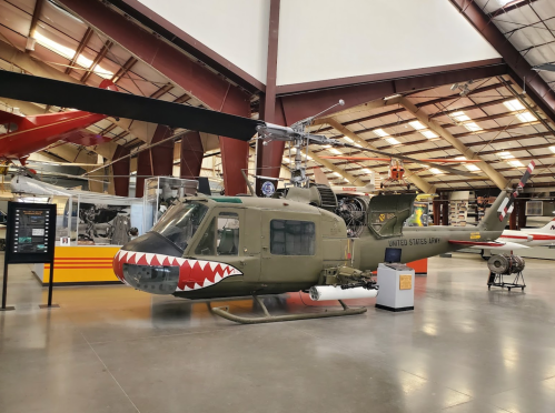 A military helicopter with a shark mouth design displayed in an aviation museum.