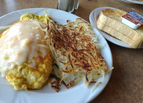 A plate with a cheesy omelet, crispy hash browns, and a slice of toast with butter on the side.