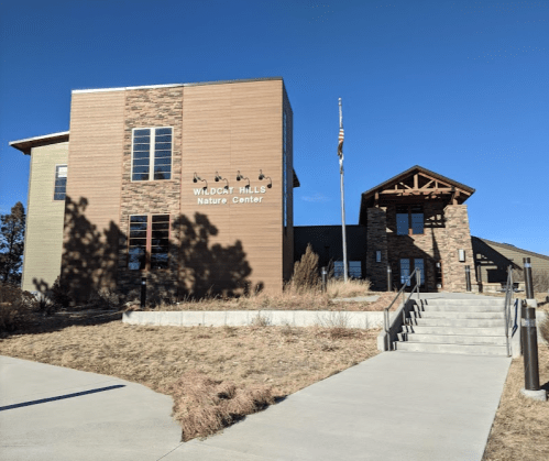 Exterior of Wildcat Hills Nature Center, featuring a modern building with stone accents and a flagpole.