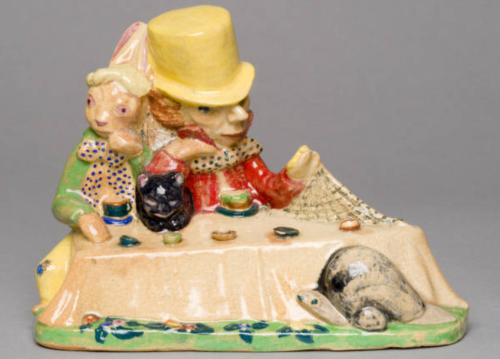 A whimsical ceramic figurine of a man in a top hat and a rabbit at a table, with a turtle nearby.