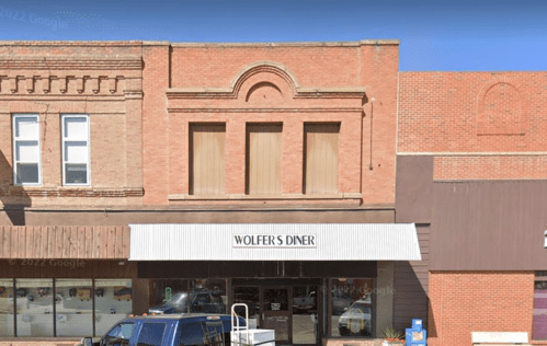 Exterior of Wolfer's Diner, a brick building with large windows and an awning, located in a small town.