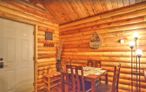 Cozy cabin interior with wooden walls, a dining table, and lanterns, creating a warm, inviting atmosphere.