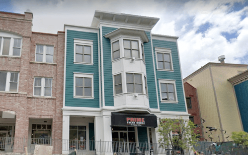 A three-story building with blue siding and a black awning labeled "Prime Steak House" at the entrance.