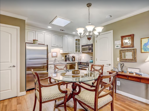 A modern kitchen with a dining table, stainless steel appliances, and warm wood accents. Bright and inviting atmosphere.