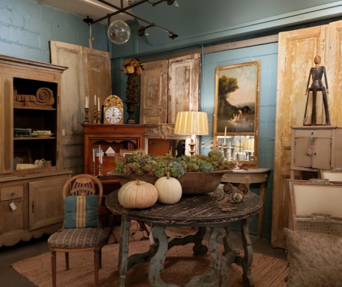 A cozy vintage shop interior featuring rustic furniture, decorative items, and autumn decor with pumpkins.