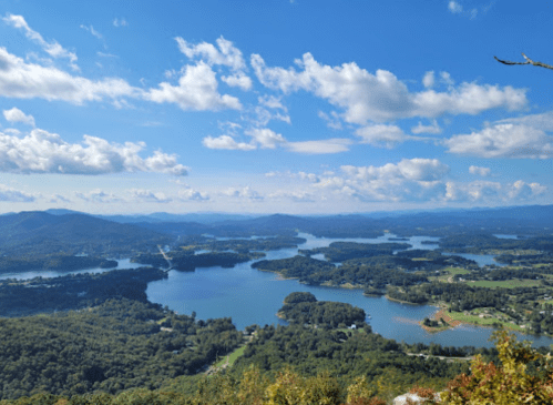 A panoramic view of lakes and mountains under a blue sky with scattered clouds.