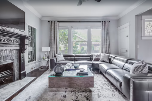 Modern living room featuring a large sectional sofa, glass coffee table, and elegant decor with natural light.