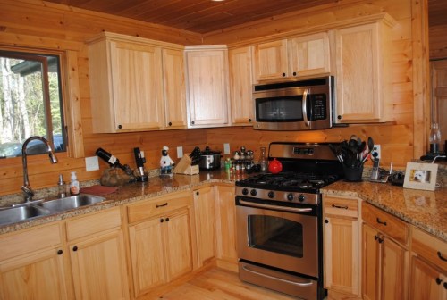 A cozy wooden kitchen featuring light wood cabinets, a stainless steel stove, and a granite countertop.