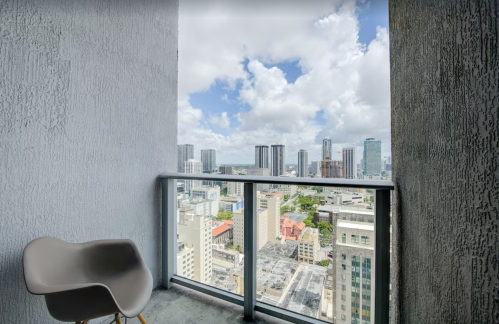 A balcony view of a city skyline with tall buildings and a partly cloudy sky.