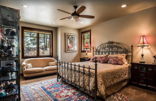 Cozy bedroom featuring a wrought iron bed, decorative pillows, a sofa, and warm lighting from bedside lamps.