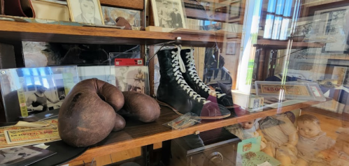 Display case featuring vintage boxing gloves, boots, and historical photographs related to boxing.