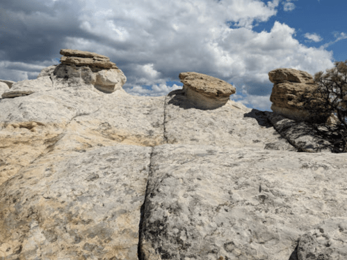 Rock formations with flat tops under a cloudy sky, showcasing a rugged landscape and natural textures.