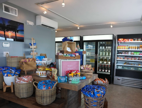 A cozy store interior featuring snacks, drinks, and a display of various packaged goods on wooden shelves and baskets.