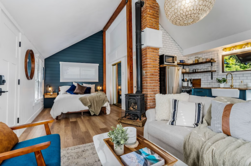 Cozy interior of a modern cabin featuring a living area, kitchen, and bedroom with rustic decor and warm lighting.