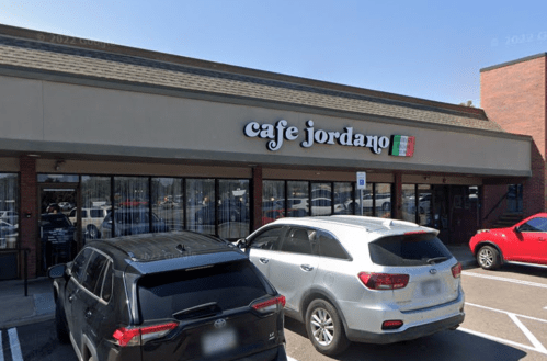 Exterior of Cafe Jordano with parked cars in front and a clear blue sky above.