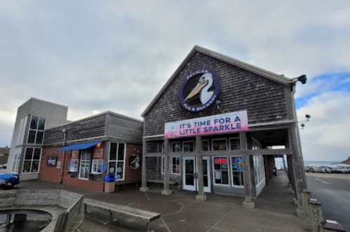 Exterior of a coastal restaurant with a large pelican sign, featuring a banner that says "It's time for a little sparkle."