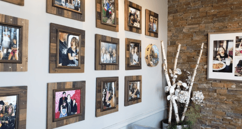 A gallery wall featuring various framed family photos in a cozy, rustic setting with stone accents.