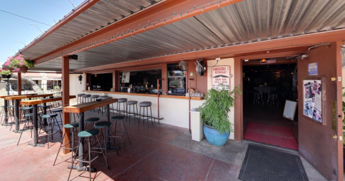 Exterior view of a bar with outdoor seating, featuring a welcoming entrance and a vibrant atmosphere.