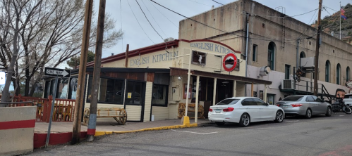 A quaint restaurant named "English Kitchen" with a vintage sign, surrounded by parked cars and a hilly backdrop.