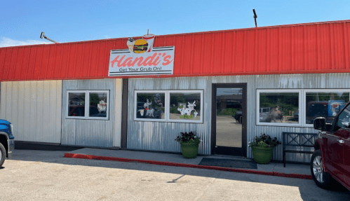 Exterior of Handi's restaurant with a red roof, large windows, and a sign that says "Get Your Grub On!" in bright letters.
