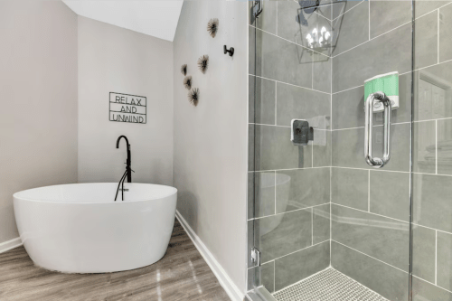 A modern bathroom featuring a freestanding tub, glass shower, and a "Relax and Unwind" sign on the wall.