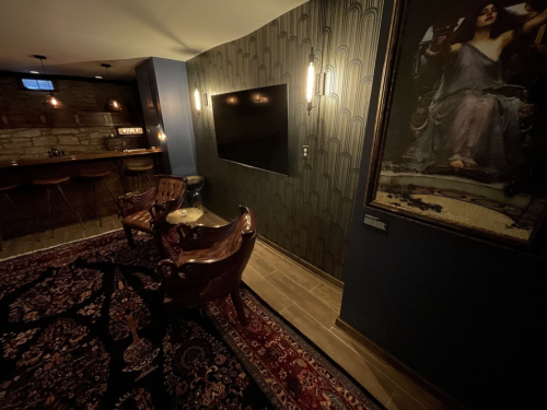 Cozy room featuring a bar area, a large TV, elegant seating, and a decorative wall with a vintage painting.