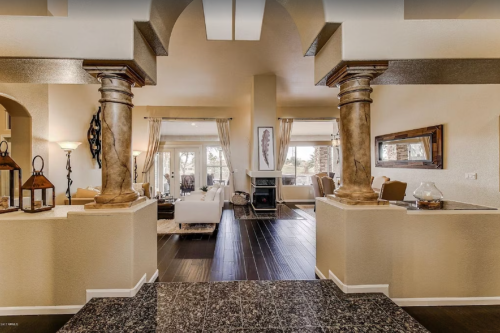 A spacious, elegantly designed living area with columns, modern furniture, and large windows letting in natural light.