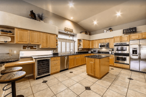 Spacious kitchen with wooden cabinets, granite countertops, stainless steel appliances, and tile flooring.