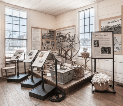 A museum exhibit featuring historical artifacts, displays about agriculture, and informational panels in a bright room.