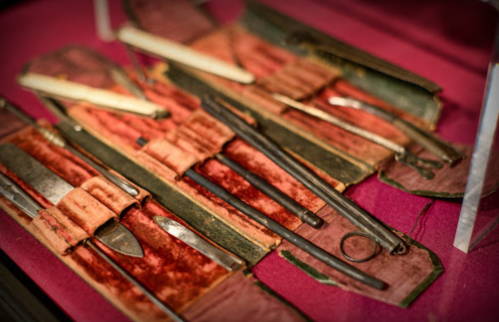 A collection of vintage surgical instruments displayed in a velvet-lined case.
