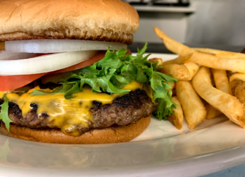 A juicy cheeseburger with lettuce, tomato, and onion, served with a side of golden French fries.