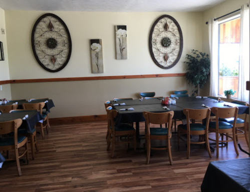 A cozy restaurant interior with wooden floors, tables set for dining, and decorative wall art.