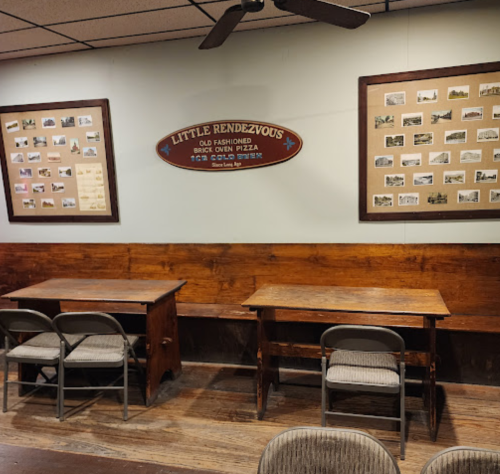 Interior of a cozy restaurant with wooden tables, chairs, and framed historical photos on the walls.