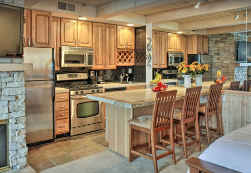 Modern kitchen with wooden cabinets, stainless steel appliances, a large island, and bar stools. Cozy and inviting atmosphere.