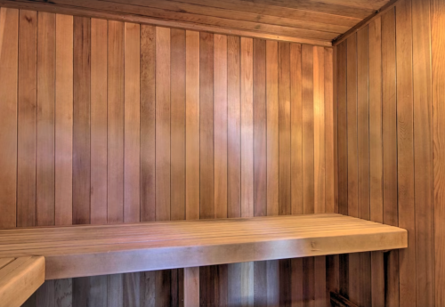 Interior of a wooden sauna with vertical paneling and a bench. Warm, inviting atmosphere.