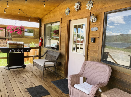 Cozy porch with a grill, seating, and decorative flowers, overlooking a scenic outdoor view.