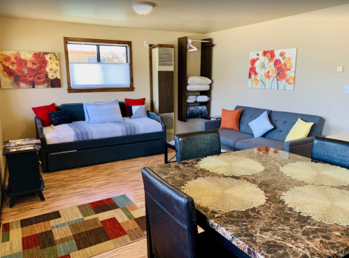 Cozy living space featuring a daybed, sofa, dining table, and colorful decor with floral artwork.