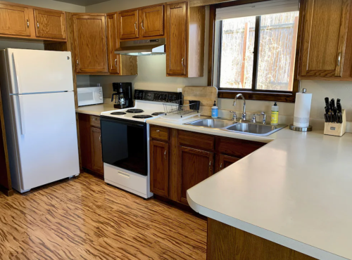 A modern kitchen with wooden cabinets, white appliances, and a countertop, featuring a sink and stove.