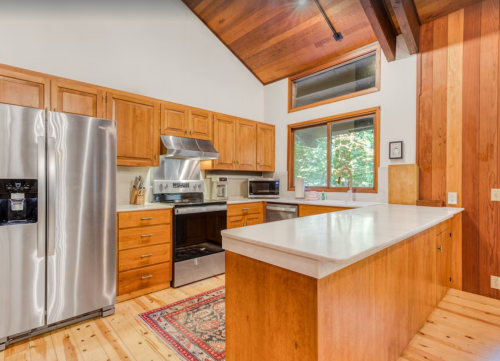 Modern kitchen with wooden cabinets, stainless steel appliances, and a large island, featuring a warm, inviting atmosphere.