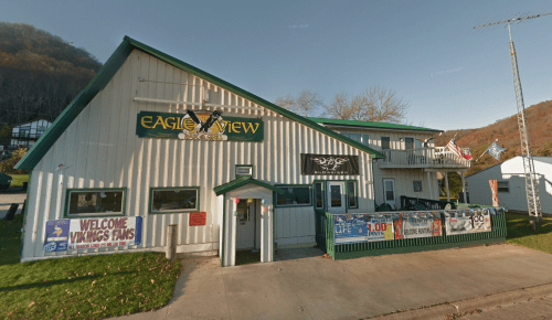 A two-story building with a green and white exterior, featuring banners and a sign for "Eagle View."