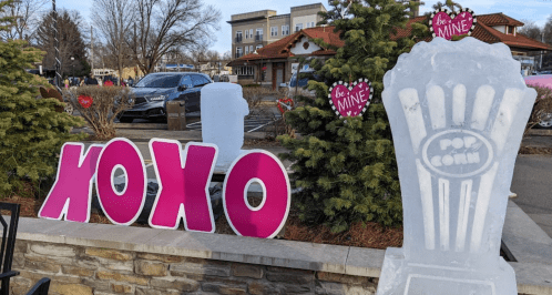 Colorful "XOXO" sign and an ice sculpture of a popcorn container in a festive outdoor setting.