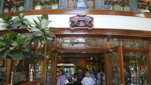 Entrance of a restaurant with wooden doors, decorative glass, and a sign reading "Established 1904." People are inside.