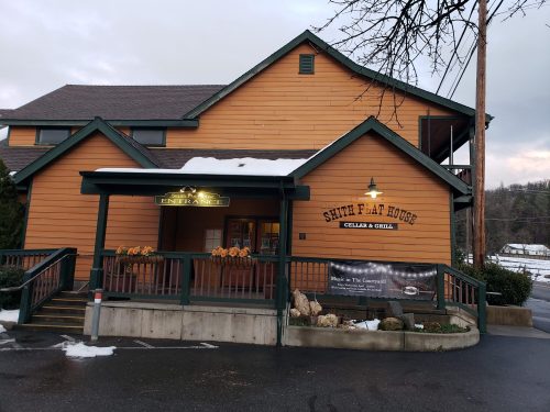 A wooden building with a sign reading "Saint Flat House" and a welcoming entrance, surrounded by snow.